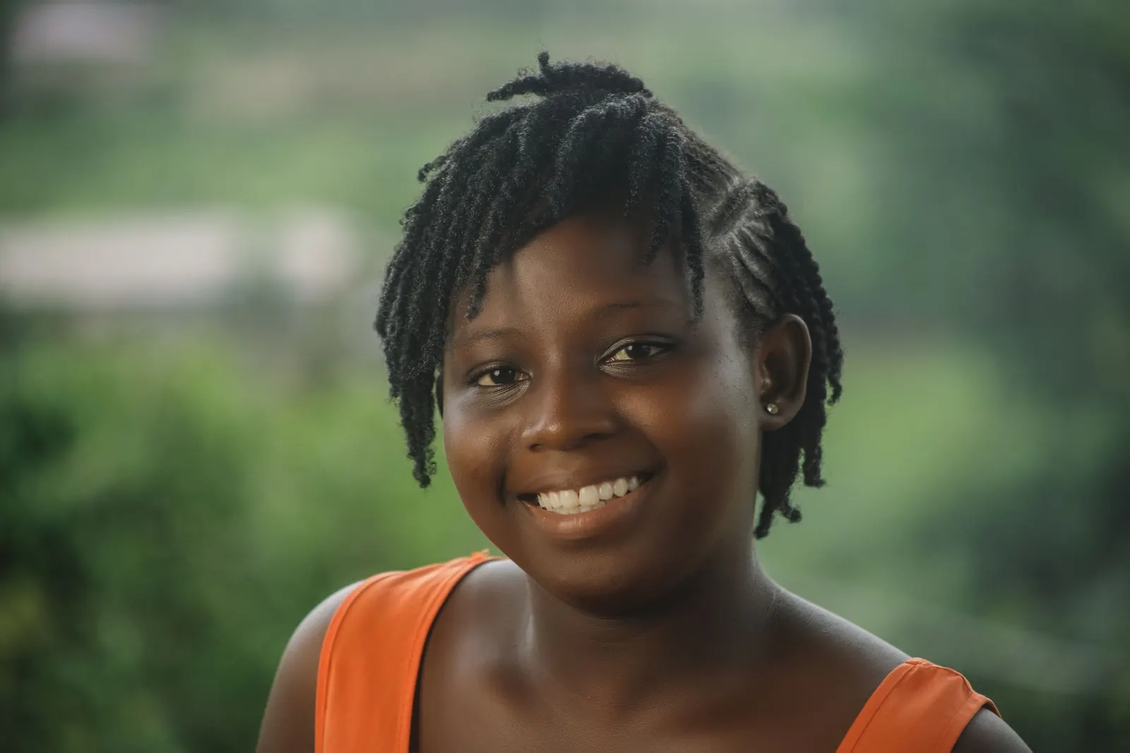 Smiling young woman with braided hair outdoors in soft natural light